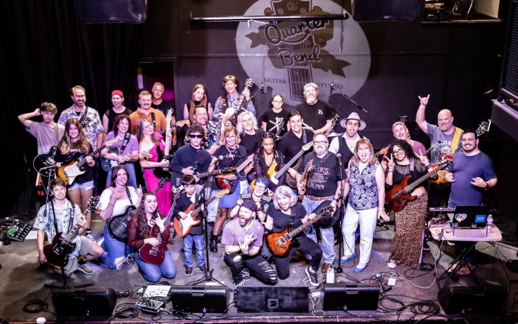About forty Quarter Bend guitar students of all ages on stage together with their guitars after a Mega Concert